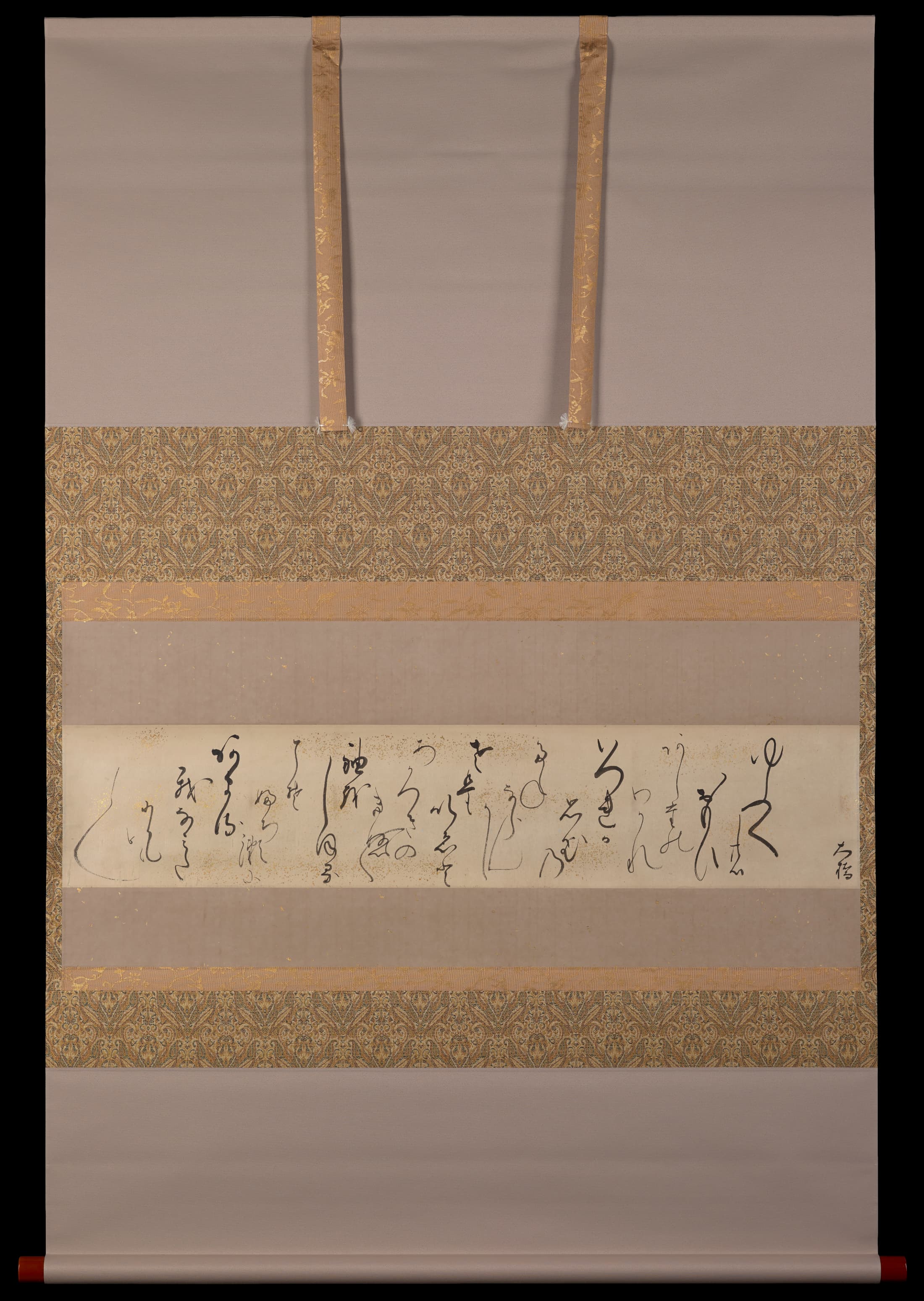 Long, horizontal sheet of beige paper speckled with gold inscribed with many short lines of cursive calligraphy at alternating heights. Calligraphy is fluid with a variety of line thicknesses